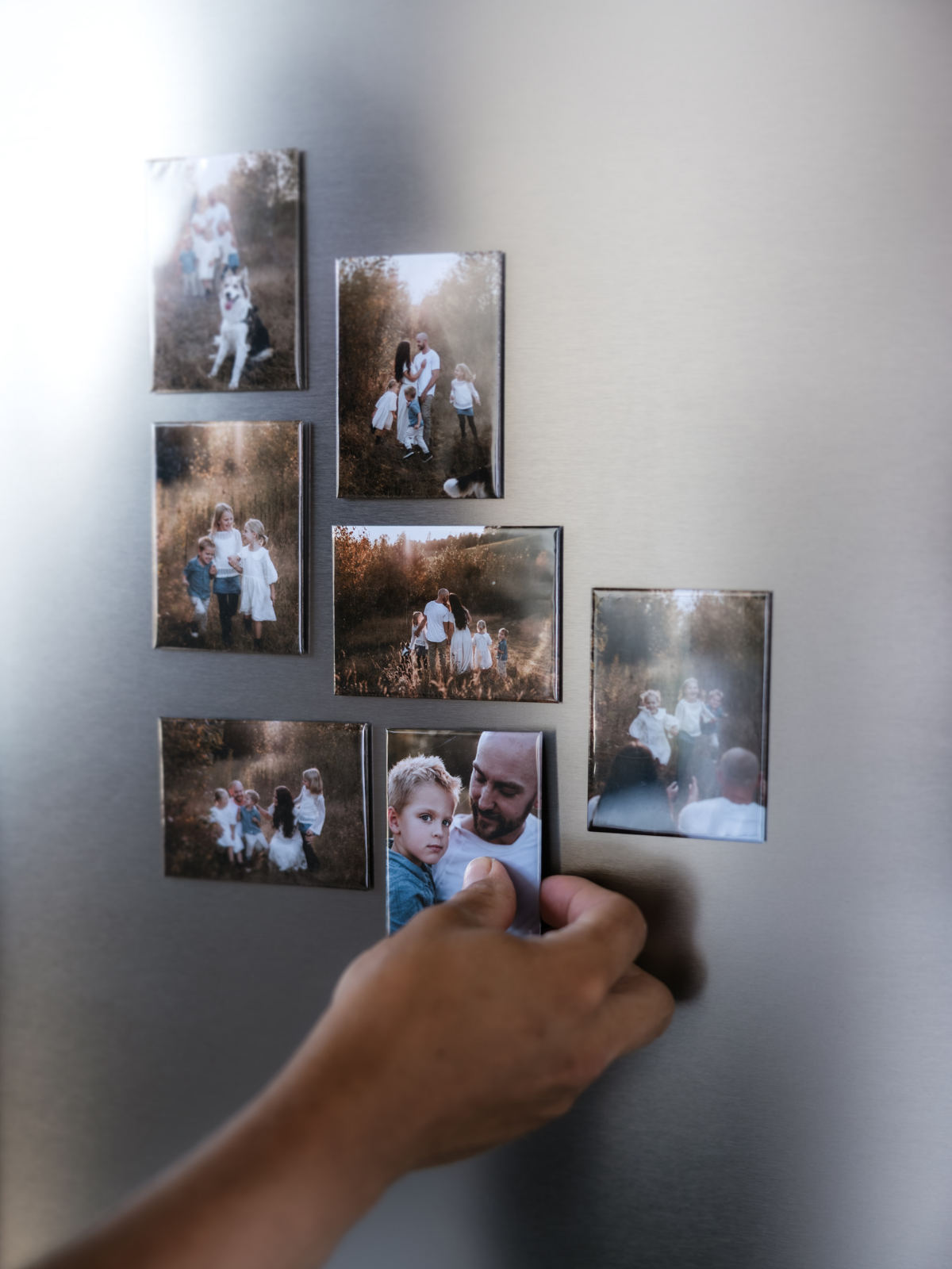 Magnets on fridge with hand placing them.